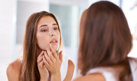 Une femme regarde ses boutons dans le miroir