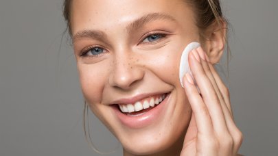Bien nettoyer sa peau Une femme se passe un coton sur le visage